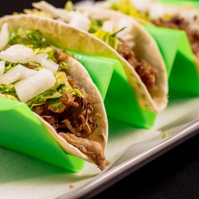 Meat tacos topped with lettuce and chopped onions in flour tortillas.