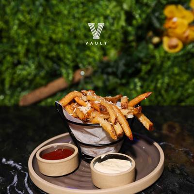 A serving of French fries, served with two dipping sauces.