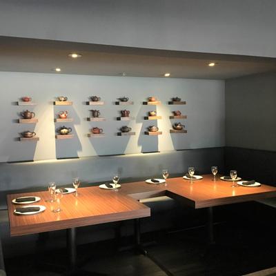 Dining area with various teapots on mounted wall shelves.