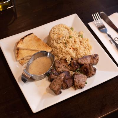 Beef souvlaki with pita tips, rice and sauce.