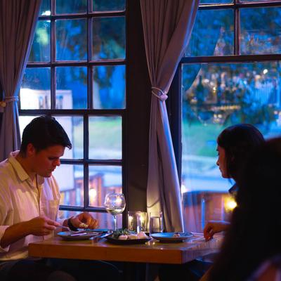 A couple having a romantic dinner at a table by the window.