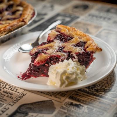 Piece of Blackberry pie served with whopped cream on the side.