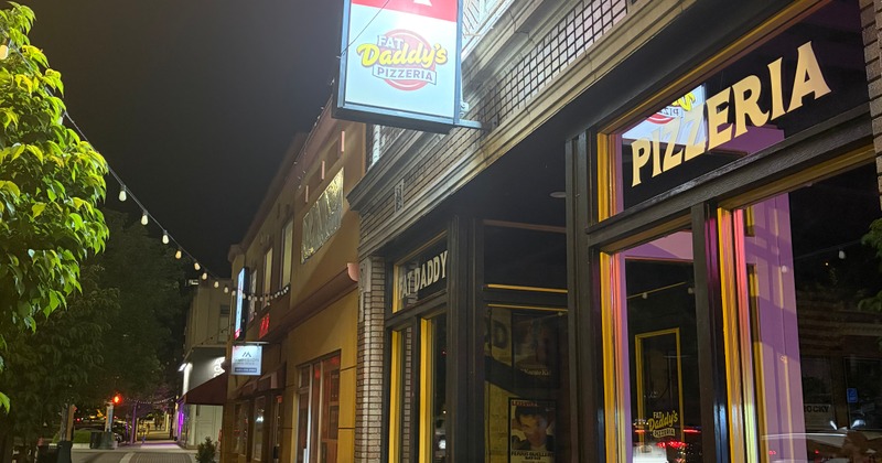 Storefront with brick facade, entrance, signage and string lights