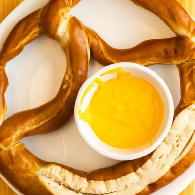 A pretzel with a cup of cheese sauce.