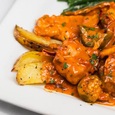 Chicken pieces with sausage, potato and sweet cherry peppers in a wine sauce.