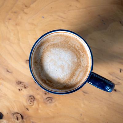 Hot Latte in a ceramic coffee mug, resting on a light wood surface.