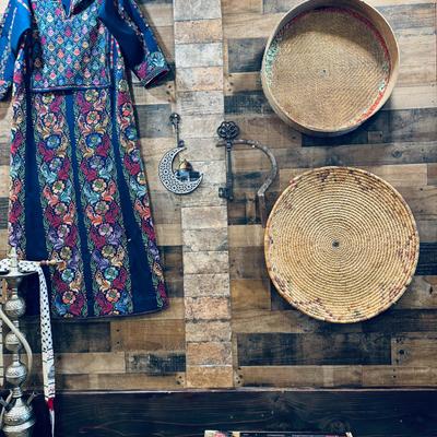 Traditional embroidered dress, woven baskets, and decorative elements on a wood-paneled wall.