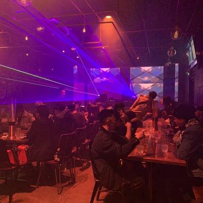 Interior with people seated at tables and purple lights.