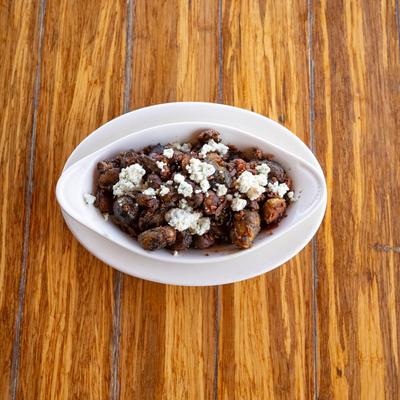 Oval white dish filled with Balsamic Brussel Sprouts, sits on a wooden table.