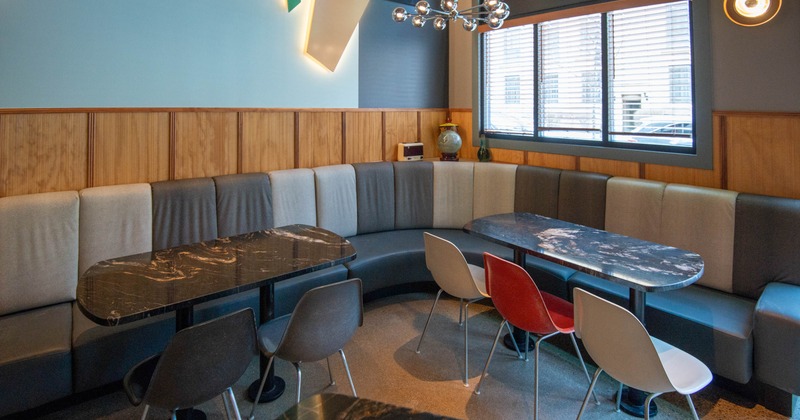 Modern dining area with curved seating, marble tables, and mismatched chairs