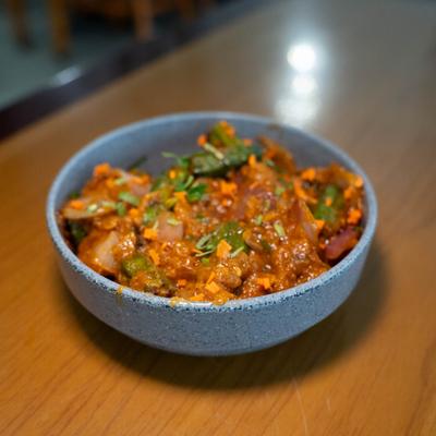 Bowl of vegetable curry topped with fresh herbs.