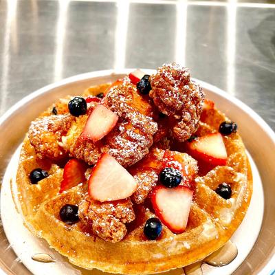Waffle topped with fried chicken and berries.