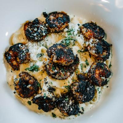Blackened shrimp pasta sprinkled with grated cheese.