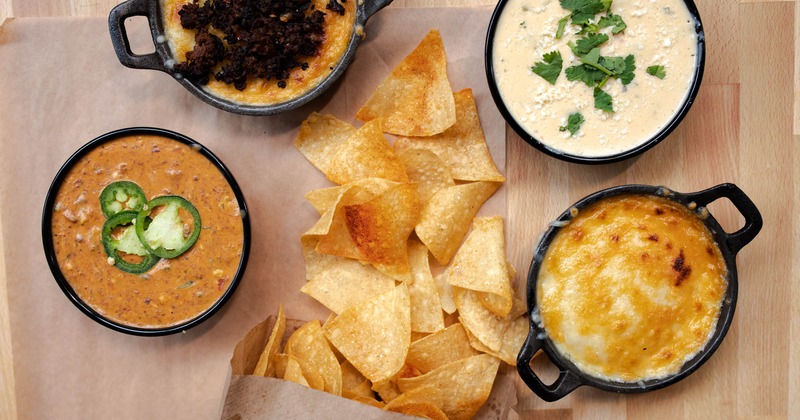 Tortilla chips and various dipping dishes, top view