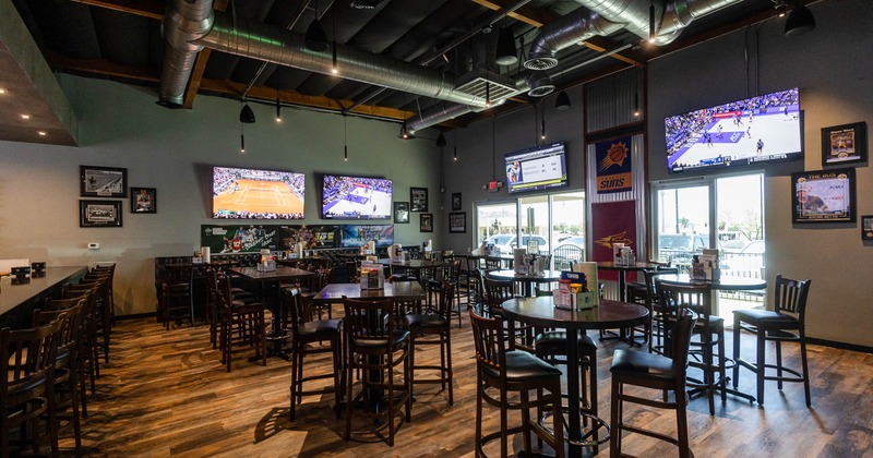 A spacious sports bar with wooden flooring and high tables
