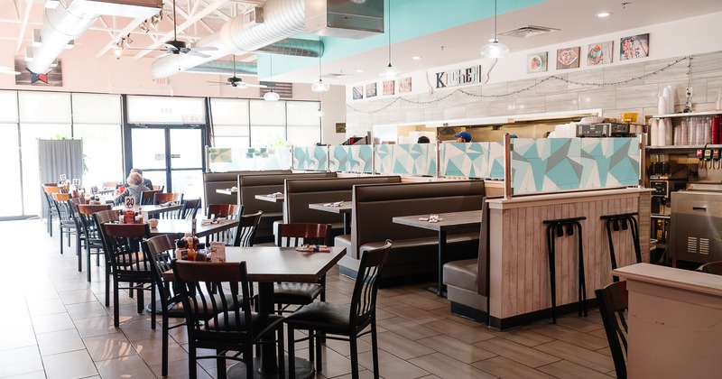Cozy and spacious interior dining area with upholstered dining booths, tables and chairs