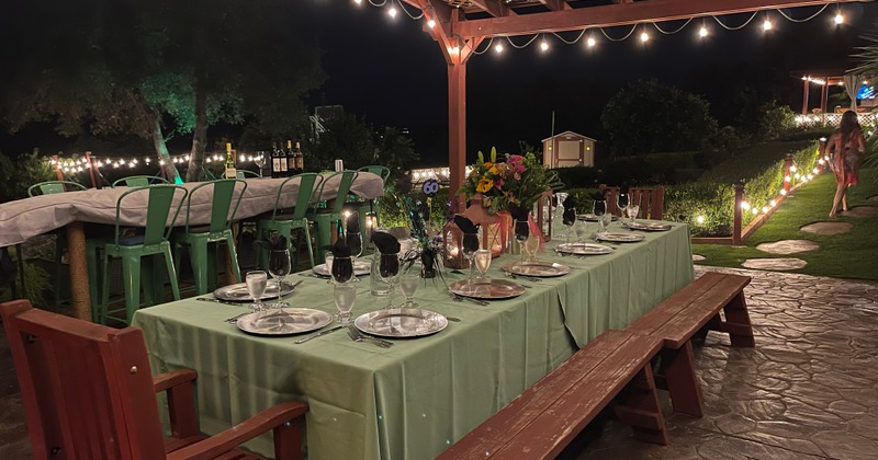 Exterior at night, a long set table in the patio