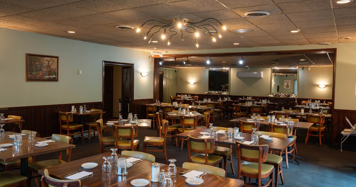 Interior  - wooden tables and chairs set with dishware and glasses, featuring a central chandelier