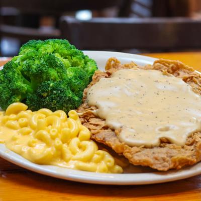Chicken fried steak served with broccoli, and mac and cheese on the plate.
