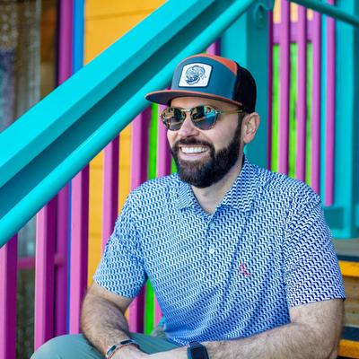 A smiling customer wearing a Chasing Tail Ale cap.