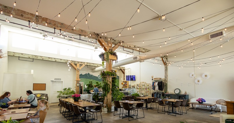 Spacious and cozy industrial-style cafe interior seating area with wooden tables and dark chairs