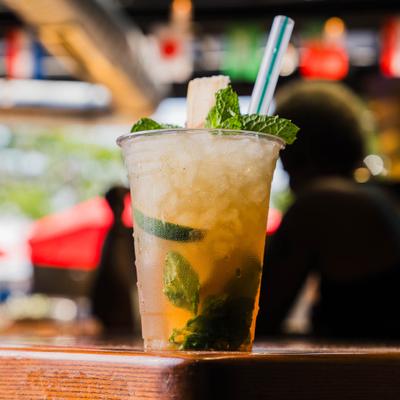 Mojito in a plastic cup served on a bar counter.