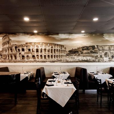 Interior featuring a mural of the Rome Colosseum, table and booth seating.