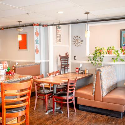 Casual diner interior with wooden tables, brown cushioned booths, and red chairs.