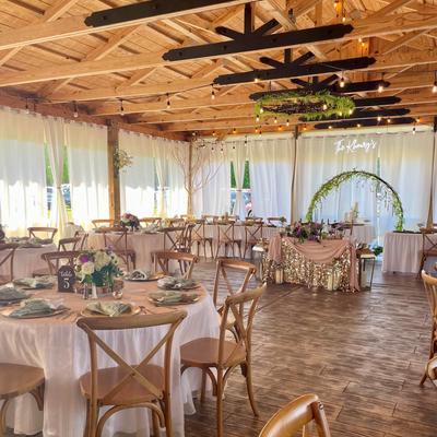 Rustic wedding reception with wooden chairs and draped white curtains.