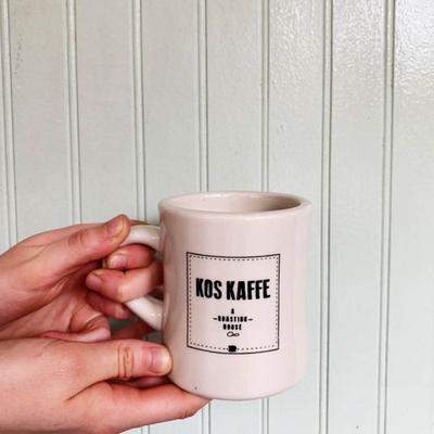 Hand holding a branded white coffee mug.