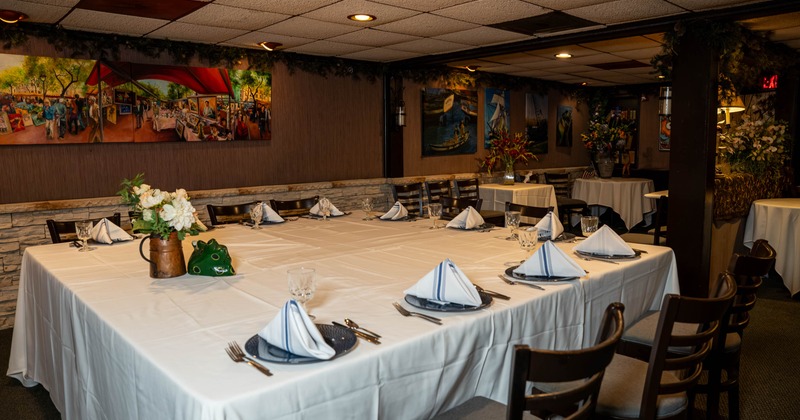 A dining room with a large table set with white tablecloth, blue plates, and folded striped napkins