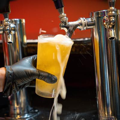 A hand pouring a beer from a dispensary.