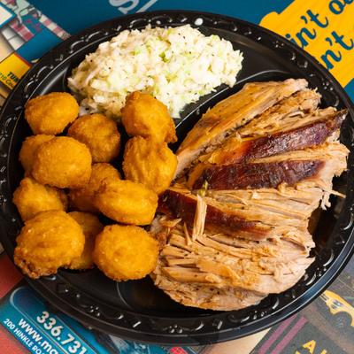 Sliced BBQ plate with coleslaw and hush puppies.
