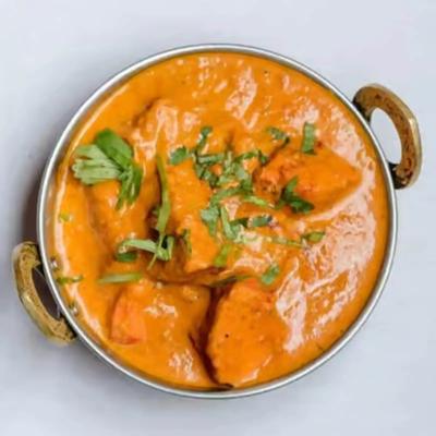 Bowl fo chicken curry with herb garnish.