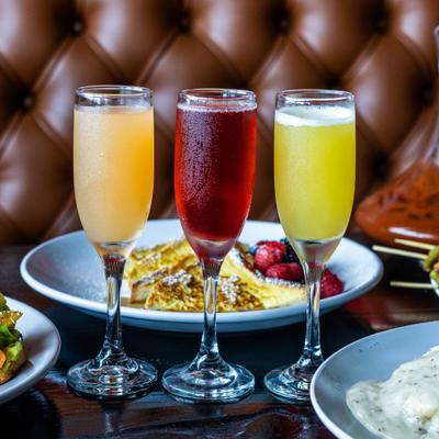 Three different Mimosa cocktails served on the table alongside French toast.