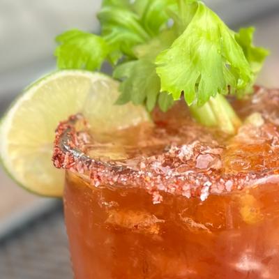 Our homemade michelada in a chilled margarita glass rimmed with tajin, garnished with celery stalk and lime.