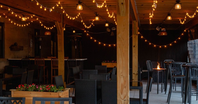 Exterior, covered seating area, regular and high seating tables, exposed wooden beams