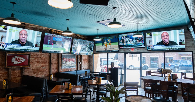 Interior, seating area, tables with chairs, TVs high on the walls, entrance, large shop windows