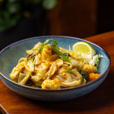 Spicy noodles with mixed vegetables served in a blue dish.