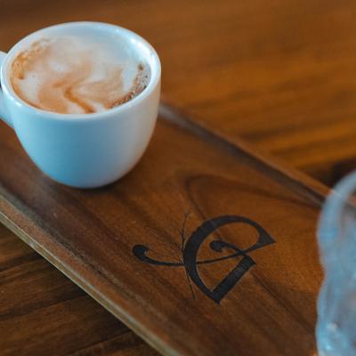 A cup of cappuccino on a branded wooden tray.