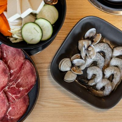 Top view of raw shrimp and clam plates, meat plate and tofu veggie bowl.