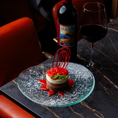 Chocolate dessert topped with strawberries on a glass plate, accompanied by red wine.