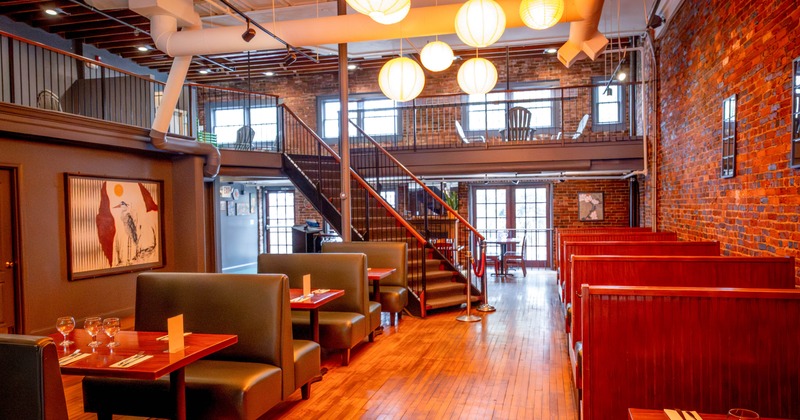 Restaurant interior with brick walls, wood floors, booth seating, and hanging paper lanterns