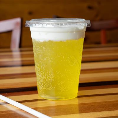 Orangesicle dirty soda served in a clear plastic cup.