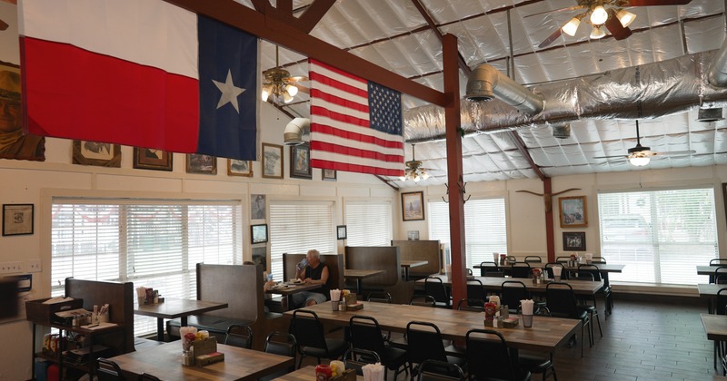 Interior space, cozy dining area with wooden tables and booth seating with simple black chairs