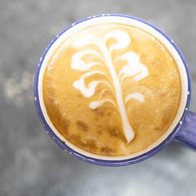 Cup of latte art in a blue mug, overhead view.