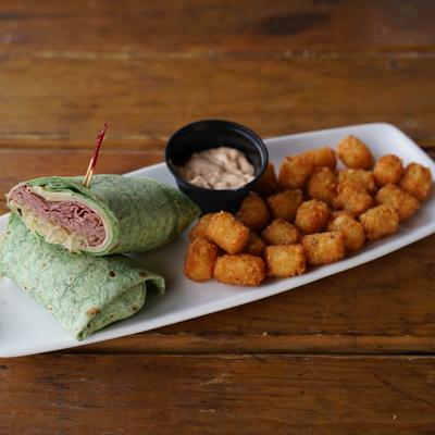 Reuben wrap with tater tots and side thousand island dressing.
