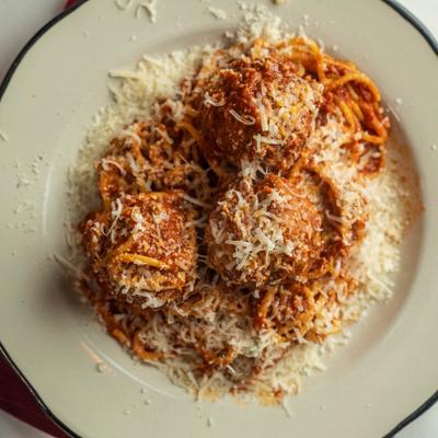 Spaghetti and meatballs topped with grated cheese.