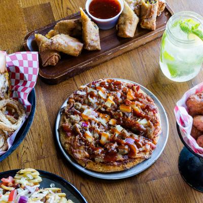 Whole pizza served on the table with other dishes and a cocktail.