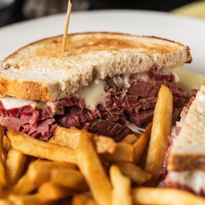 Reuben sandwich with melted cheese and fries.